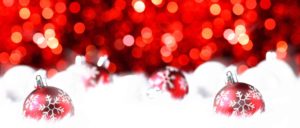 Immagine che rappresenta degli addobbi natalizi: palline di Natale rosse sulla neve bianca. L'intento è far sentire il visitatore del sito a casa, proponendo prodotti di bellezza di qualità, di cui può fidarsi